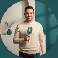 Portrait of male tech influencer Tom Baker holding the 2in1 Sprayer Comb Hairbrush, smiling. He has short, dark hair and is w